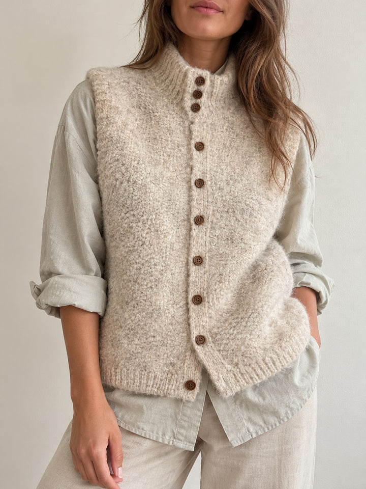 Model wearing the beige fluffy knit button-front vest with stand collar over a shirt